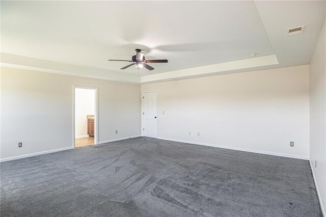 carpeted spare room featuring ceiling fan and a raised ceiling