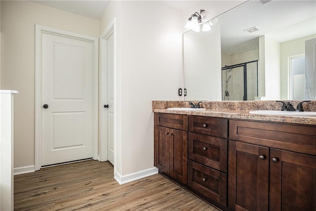 bathroom with hardwood / wood-style flooring, a shower with door, and vanity