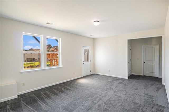 unfurnished room featuring dark colored carpet