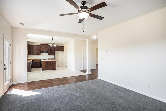 unfurnished living room featuring ceiling fan with notable chandelier and light hardwood / wood-style floors