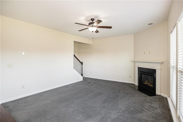 unfurnished living room with ceiling fan and dark colored carpet