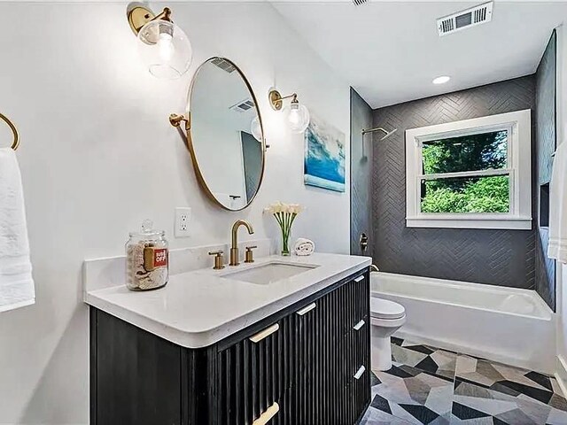 full bathroom featuring toilet, vanity, and tiled shower / bath