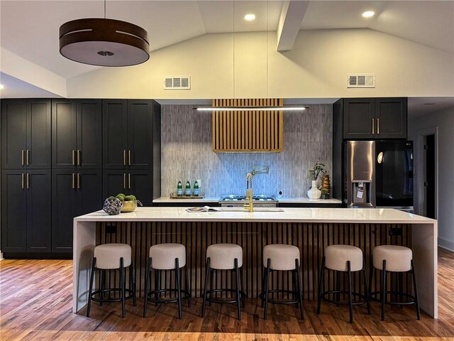 kitchen with a kitchen bar, stainless steel fridge, and an island with sink