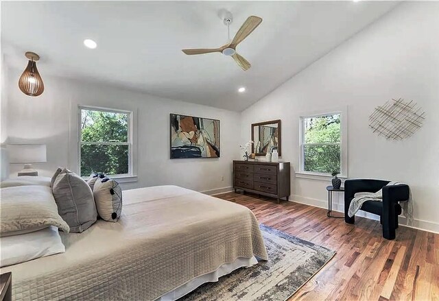 bedroom featuring ceiling fan, multiple windows, dark hardwood / wood-style floors, and vaulted ceiling