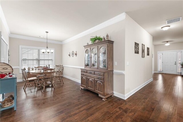 dining room with an inviting chandelier, dark wood-type flooring, and ornamental molding