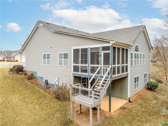 rear view of property with a sunroom, a patio area, and a lawn