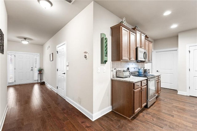 kitchen featuring light stone countertops, backsplash, stainless steel appliances, and dark hardwood / wood-style floors