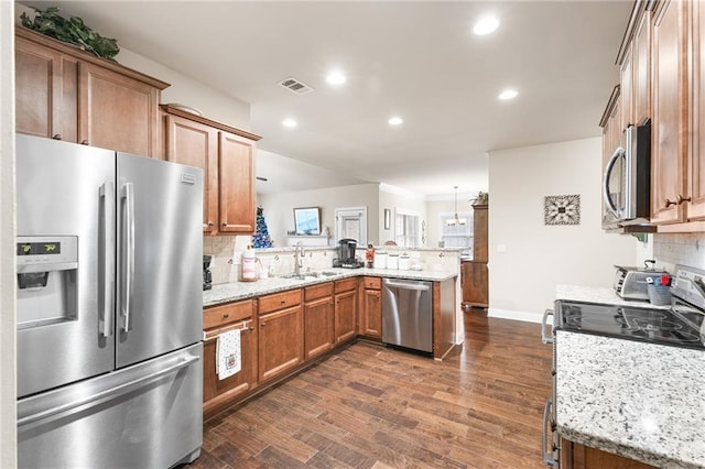 kitchen featuring decorative light fixtures, sink, decorative backsplash, kitchen peninsula, and stainless steel appliances