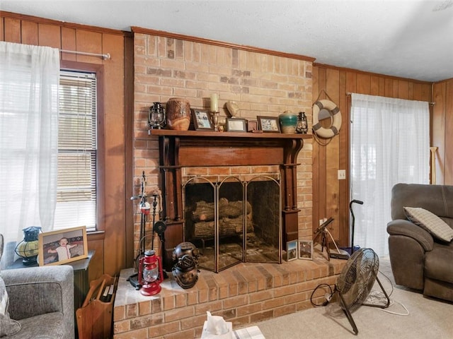 living room featuring a fireplace, ornamental molding, carpet flooring, and wood walls