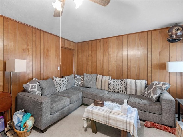 living room with ceiling fan, wood walls, and light colored carpet