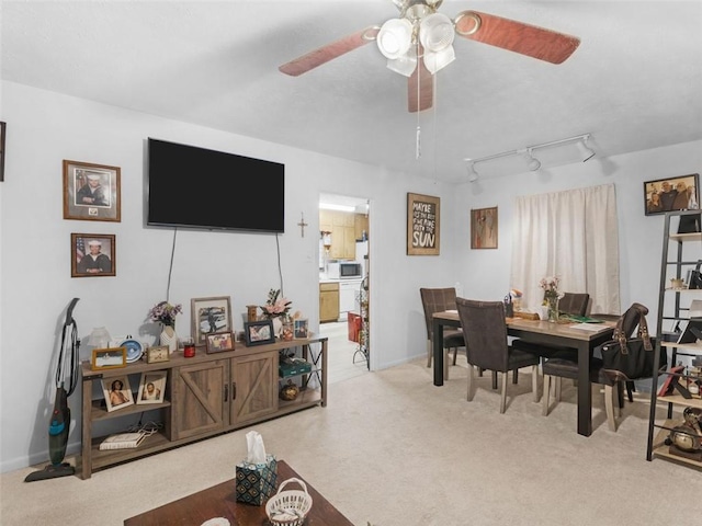 dining room featuring rail lighting, ceiling fan, and light colored carpet