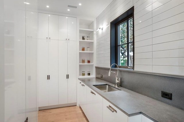 kitchen with white cabinetry, sink, decorative backsplash, and light hardwood / wood-style floors