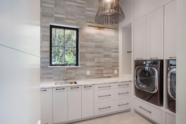 clothes washing area featuring washer and dryer, sink, cabinets, and light tile patterned flooring