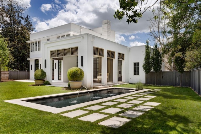 rear view of property with a fenced in pool, pool water feature, and a lawn