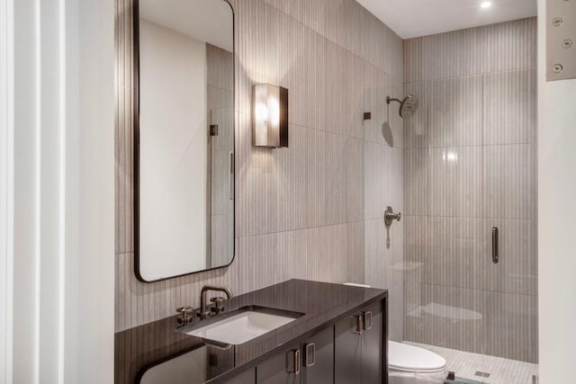 bathroom featuring vanity, a shower with shower door, and toilet