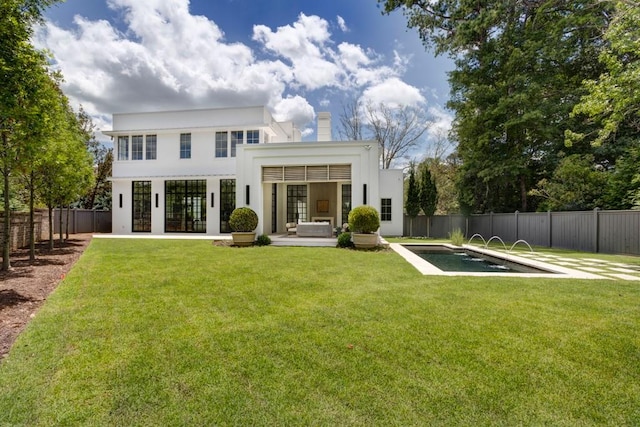 rear view of house with a fenced in pool and a lawn