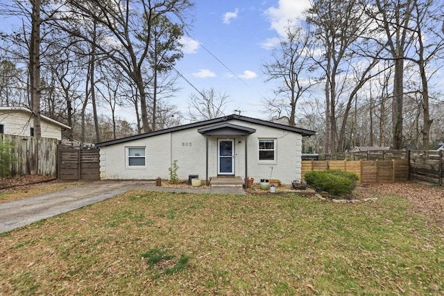 view of front of home with driveway, fence, a front lawn, and brick siding