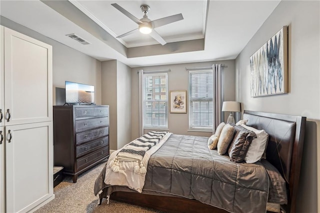 carpeted bedroom featuring ceiling fan and a tray ceiling