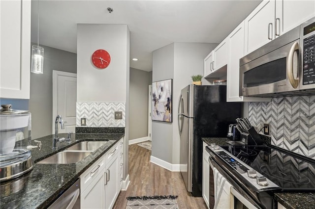 kitchen with decorative backsplash, stainless steel appliances, sink, decorative light fixtures, and white cabinetry