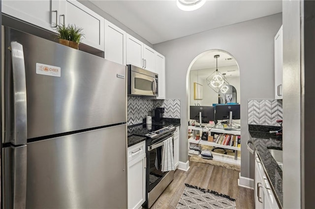 kitchen with decorative backsplash, dark stone countertops, white cabinetry, and stainless steel appliances