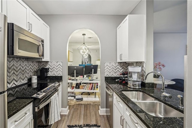 kitchen featuring white cabinets, stainless steel appliances, and dark stone counters