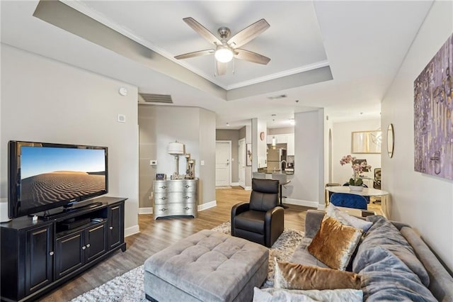 living room featuring a tray ceiling, crown molding, ceiling fan, and hardwood / wood-style flooring