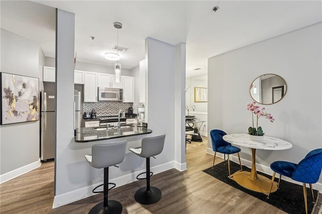 kitchen with white cabinets, sink, decorative backsplash, appliances with stainless steel finishes, and decorative light fixtures