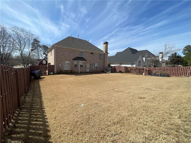 back of property with brick siding, a lawn, and a fenced backyard