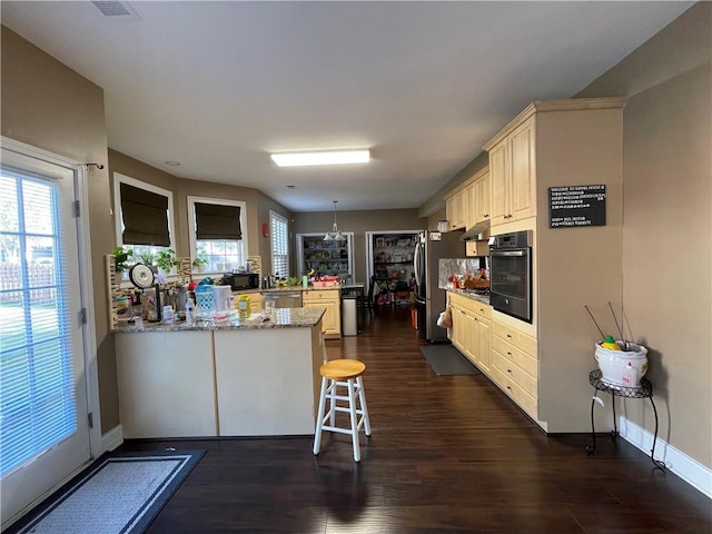 kitchen featuring dark hardwood / wood-style flooring, kitchen peninsula, stainless steel appliances, and a breakfast bar area