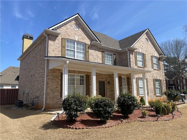 view of front of house with brick siding, fence, and a chimney