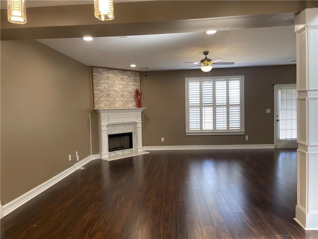 unfurnished living room with dark wood-style floors, ceiling fan, baseboards, and a high end fireplace