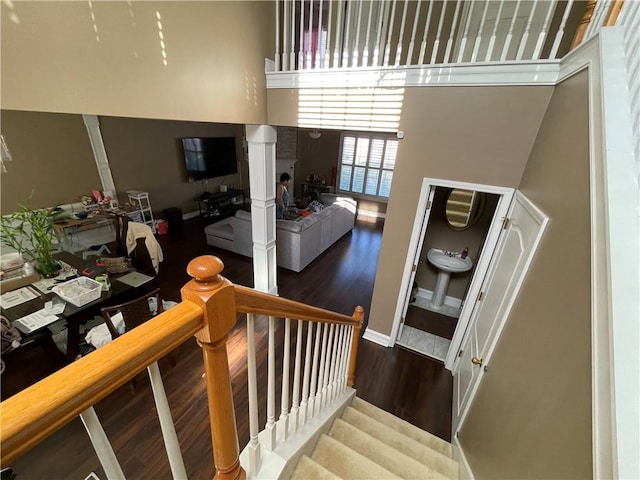 stairway with wood-type flooring and a high ceiling