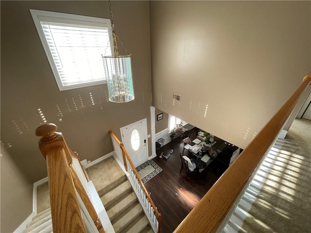 staircase with a towering ceiling and wood-type flooring