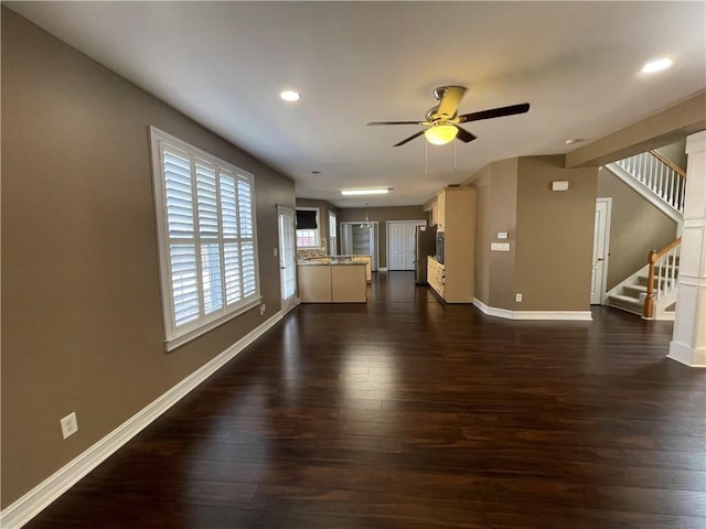 unfurnished living room with baseboards, ceiling fan, stairway, dark wood-type flooring, and recessed lighting