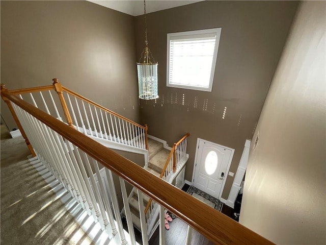 staircase with hardwood / wood-style flooring and a notable chandelier