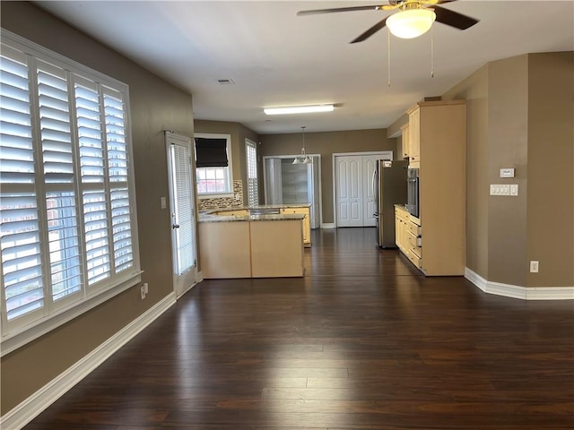 kitchen with appliances with stainless steel finishes, a wealth of natural light, dark wood-style flooring, and a peninsula