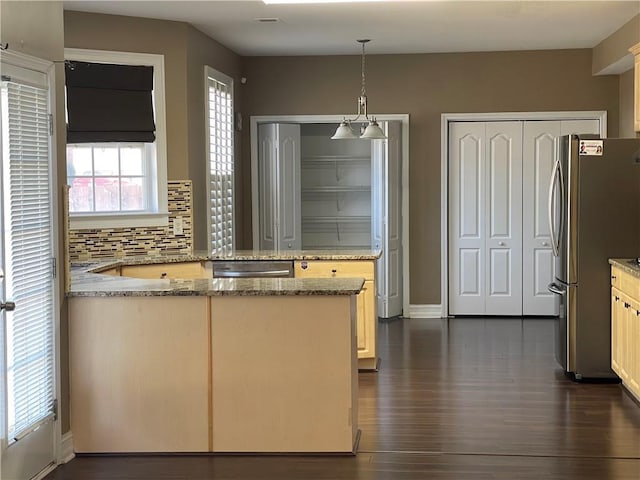 kitchen with dark wood-style floors, a peninsula, appliances with stainless steel finishes, and backsplash