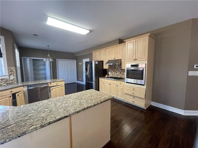 kitchen featuring dark wood finished floors, light brown cabinetry, appliances with stainless steel finishes, under cabinet range hood, and baseboards