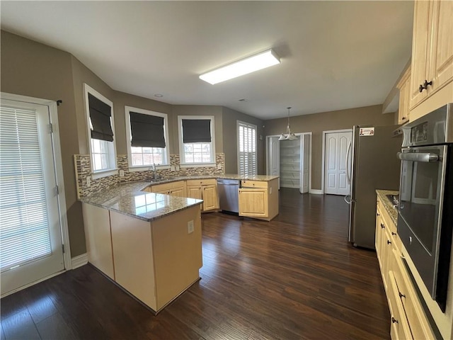 kitchen featuring decorative backsplash, appliances with stainless steel finishes, dark wood-style flooring, a peninsula, and light brown cabinets