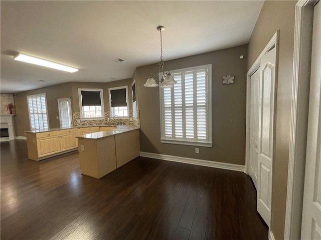 kitchen featuring baseboards, a peninsula, dark wood finished floors, and a healthy amount of sunlight