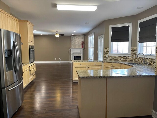 kitchen with a peninsula, appliances with stainless steel finishes, a sink, and light brown cabinetry