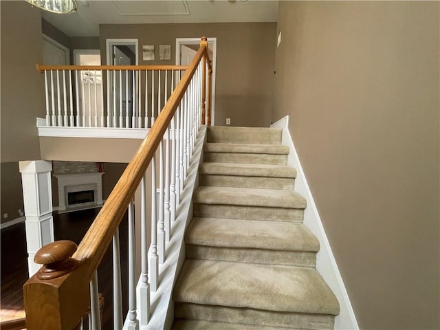 stairway with a fireplace and baseboards