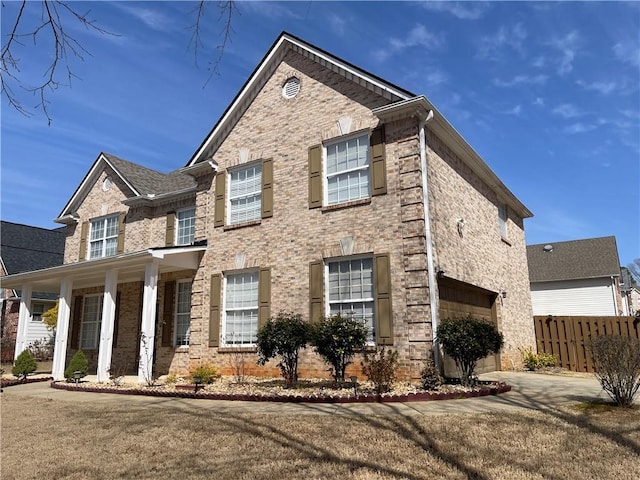 view of front of home featuring a garage, driveway, brick siding, and fence