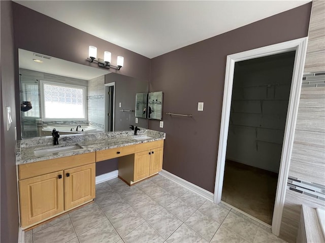 bathroom featuring tile patterned flooring, a garden tub, a sink, and baseboards