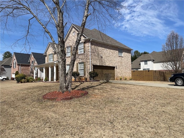 view of side of home with brick siding, a lawn, an attached garage, and fence