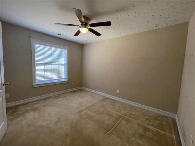 empty room featuring ceiling fan, visible vents, and baseboards