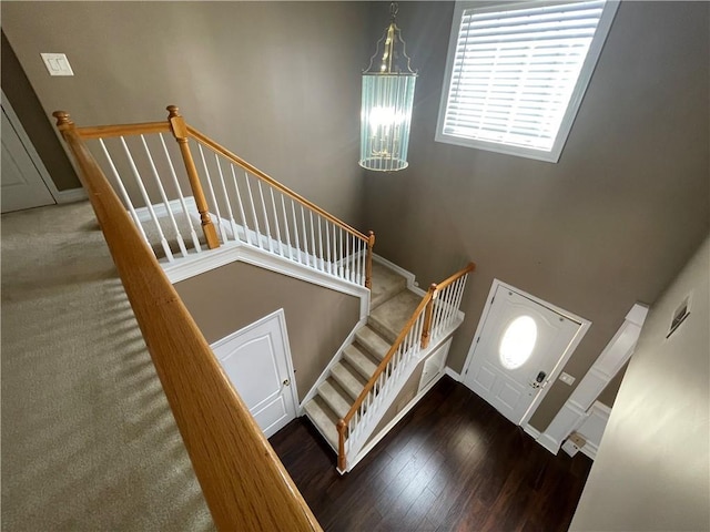 stairs featuring wood finished floors, a towering ceiling, and baseboards