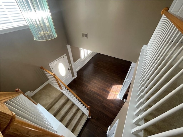 stairway featuring wood finished floors, visible vents, and baseboards