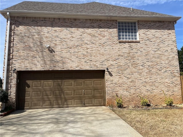 view of front facade featuring a garage, roof with shingles, and brick siding