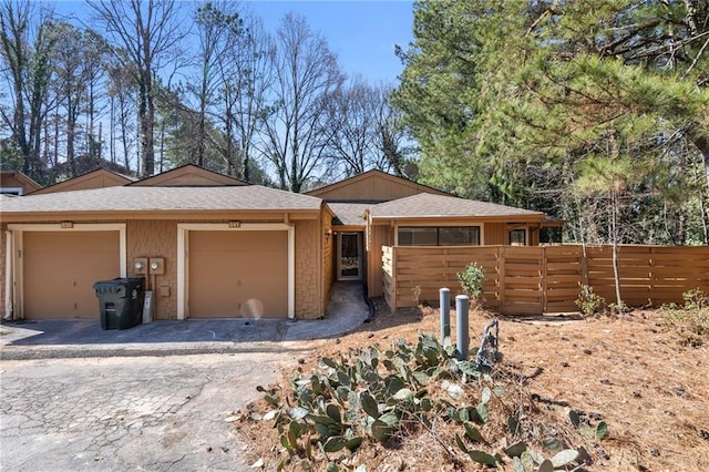 ranch-style home featuring an attached garage, driveway, and fence